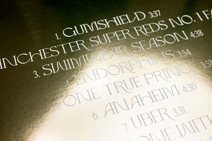 Rather than selecting a few discreet areas to highlight, this album cover does the reverse giving the effect of text etched into a gold block.